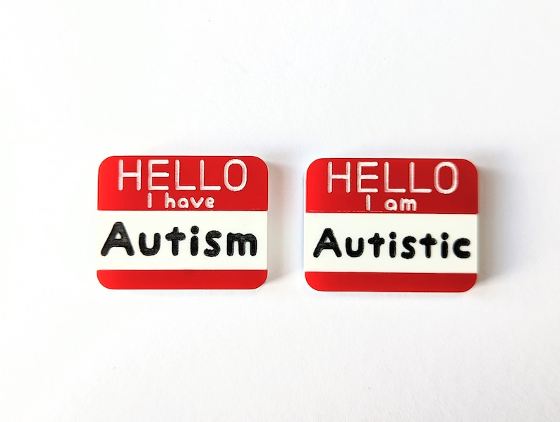 May include: Two red name tags with white lettering. The left tag says "HELLO I have Autism". The right tag says "HELLO I am Autistic".