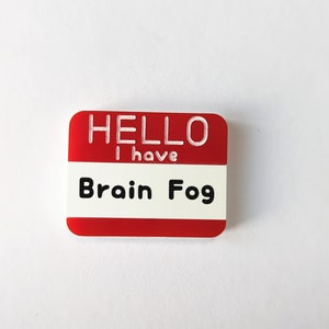 May include: Red name tag with white text that reads "HELLO I have Brain Fog".