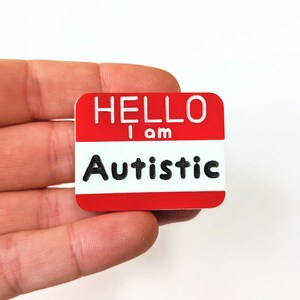 May include: Red name tag with white lettering that reads "Hello I am Autistic".