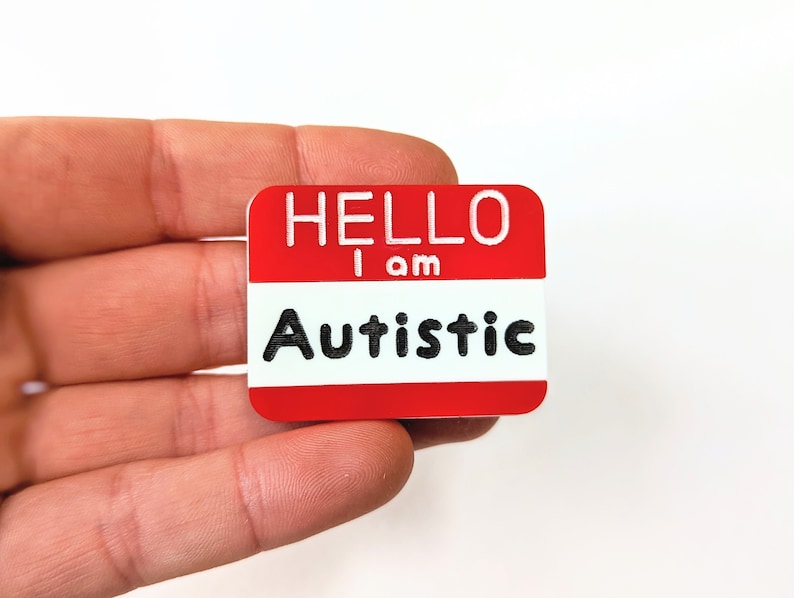 May include: Red name tag with white lettering that reads "Hello I am Autistic".