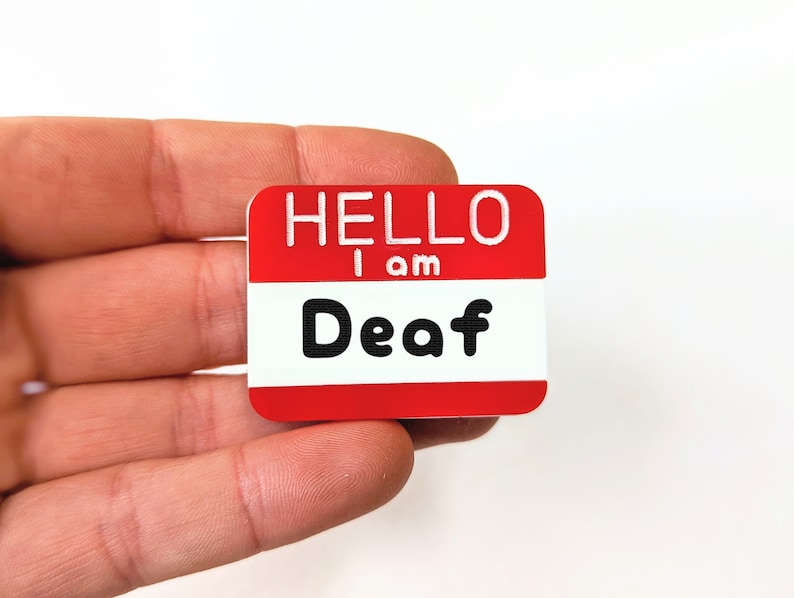 May include: A red name tag with white lettering that reads "HELLO I am Deaf".