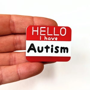 May include: Red name tag with white text that reads "Hello I have Autism".