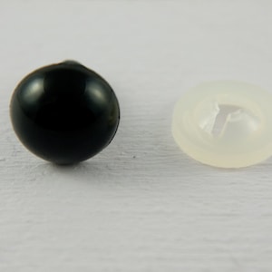 May include: A black plastic safety eye with a clear plastic washer. The eye is about 1 inch in diameter.