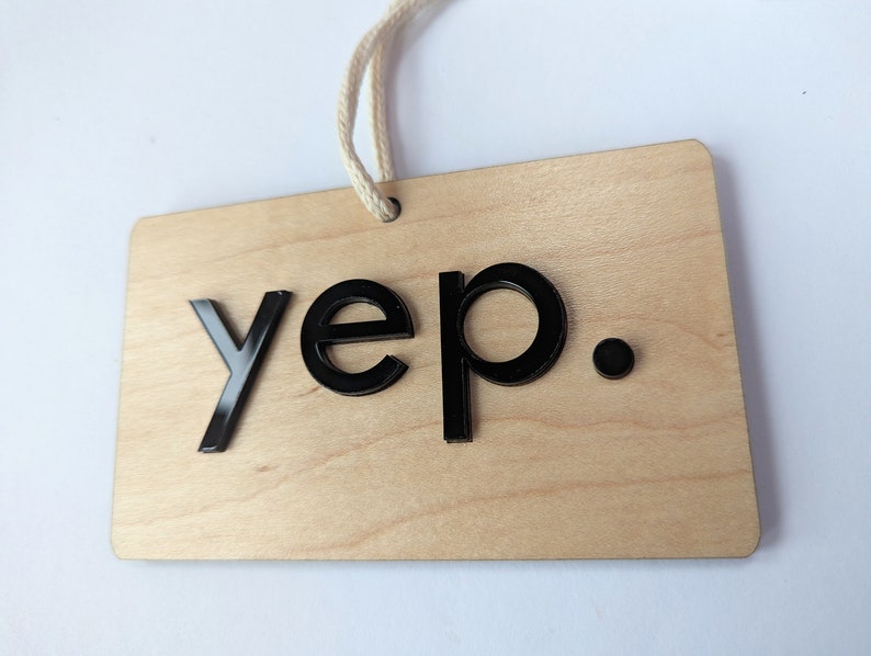 Puede incluir: Un letrero de madera con la palabra "yep." escrita en letras negras.