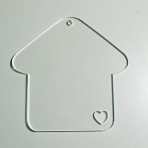 Peut inclure: Une décoration en forme de maison en acrylique transparent avec une petite découpe en forme de cœur. La décoration a un trou en haut pour l'accrocher.