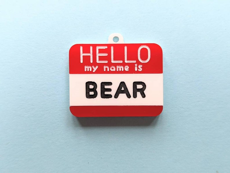 May include: Red and white name tag with the text "HELLO my name is BEAR" printed in white.