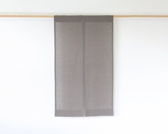Puede incluir: Un par de cortinas de lino gris colgadas de una barra de madera contra una pared blanca. Las cortinas son rectangulares, con un diseño minimalista. La tela es de color liso con una textura sutil, adecuada para un interior moderno.