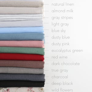 May include: A stack of folded fabric samples in various colors, including pure white, natural linen, and dusty pink. The samples are labeled with their respective color names, such as "blue sky" and "red wine."