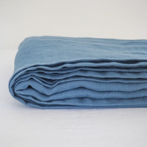 Può includere: Un tessuto di lino blu piegato. Il tessuto è morbido e ha una texture naturale.