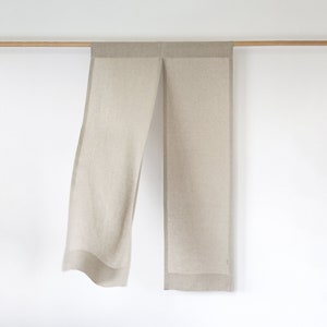 May include: A pair of beige linen curtains with a subtle texture hanging from a wooden rod.