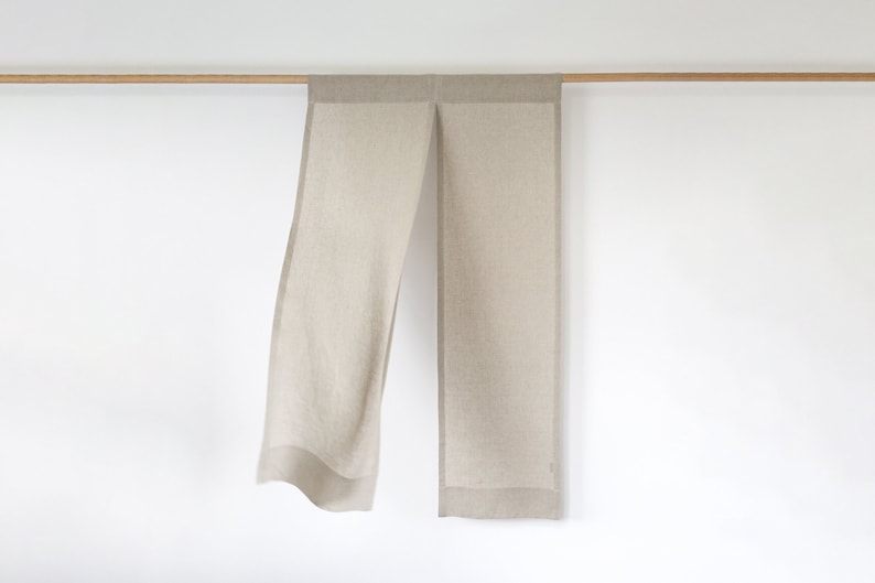 May include: A pair of beige linen curtains with a subtle texture hanging from a wooden rod.