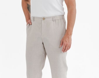 May include: A pair of light beige linen pants with a button and zipper closure. The pants have a straight leg and a relaxed fit.