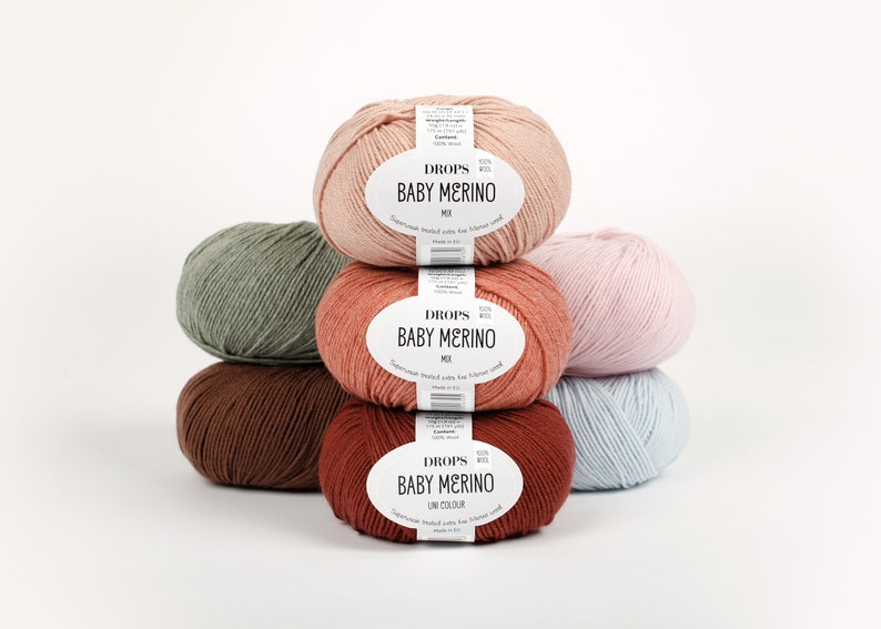 May include: A stack of five balls of yarn in different colors, including green, brown, pink, and blue. Each ball has a white label that reads "DROPS BABY MERINO".