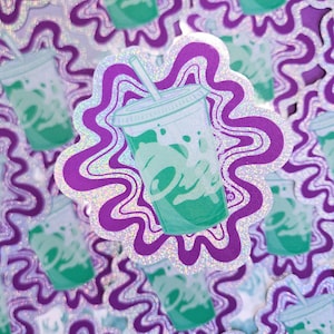 May include: A holographic sticker depicting a green and white beverage cup with a straw, set against a purple and silver wavy background. The cup has the word "Taco" on it. The sticker is surrounded by similar stickers.