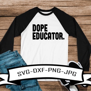 May include: A white and black baseball tee shirt with the text "Dope Educator." The shirt is on a wood background with a pair of jeans and shoes.