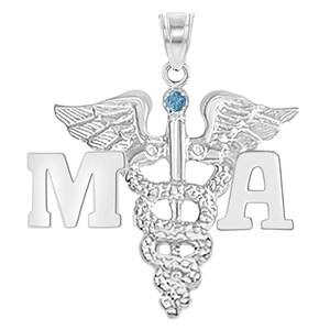 May include: Silver medical pendant necklace with a caduceus symbol and the letters 'MA' on either side. The caduceus has a blue gemstone at the top.