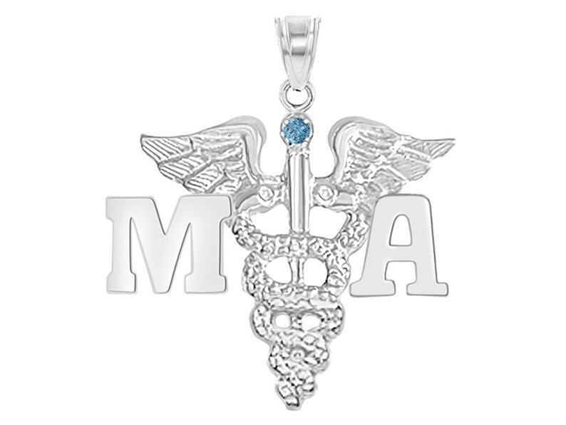 May include: Silver medical pendant necklace with a caduceus symbol and the letters 'MA' on either side. The caduceus has a blue gemstone at the top.