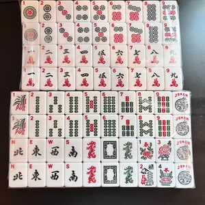 May include: A complete set of white Mahjong tiles, featuring various symbols, numbers, and Chinese characters in red and black. The tiles are arranged in rows, showcasing the different suits and special tiles, including Jokers.