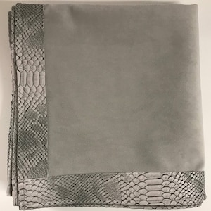 Peut inclure: Une couverture en fourrure grise avec une bordure à motif de peau de serpent. La couverture est douce et moelleuse, idéale pour ajouter une touche de luxe à n'importe quelle pièce.