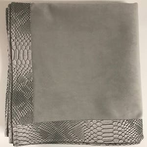 Peut inclure: Une couverture en fourrure grise avec une bordure à motif de peau de serpent. La couverture est douce et moelleuse, idéale pour ajouter une touche de luxe à n'importe quelle pièce.