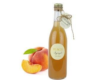 May include: A clear glass bottle of peach syrup with a gold cap and a paper tag tied with twine. The bottle has a round label that reads "PEACH Syrup 100% Natural". A whole peach and a peach slice are next to the bottle.