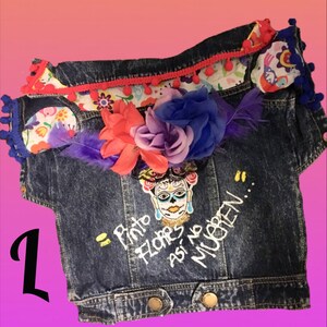 May include: A blue denim jacket with a colorful floral design, a sugar skull, and the text "Pinto Flores, asi no mueren..." embroidered on the front.