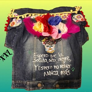 May include: A blue denim jacket with embroidered flowers, feathers, and a skull with a quote in Spanish that reads "Espero que la salida sea alegre, Y espero no volver nunca m&aacute;s".