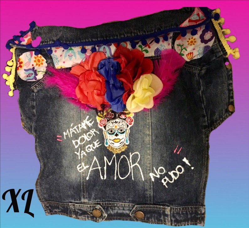 May include: A blue denim jacket with a floral trim and a skull with flowers design. The jacket has the text "M&aacute;t&aacute;me Dolor Ya Que El Amor No Pudo!" embroidered on the front.