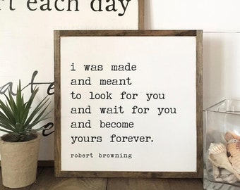 May include: Two framed wooden signs with white backgrounds and black text. One sign reads "start each day." The other sign displays a Robert Browning quote: "I was made and meant to look for you and wait for you and become yours forever."