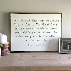 May include: A white wooden sign with a black typewriter font quote by C.S. Lewis: "...now at last they were beginning Chapter One of The Great Story no one else on earth has ever read, which goes on forever; in which every chapter is better than the one before. - C.S. LEWIS -"