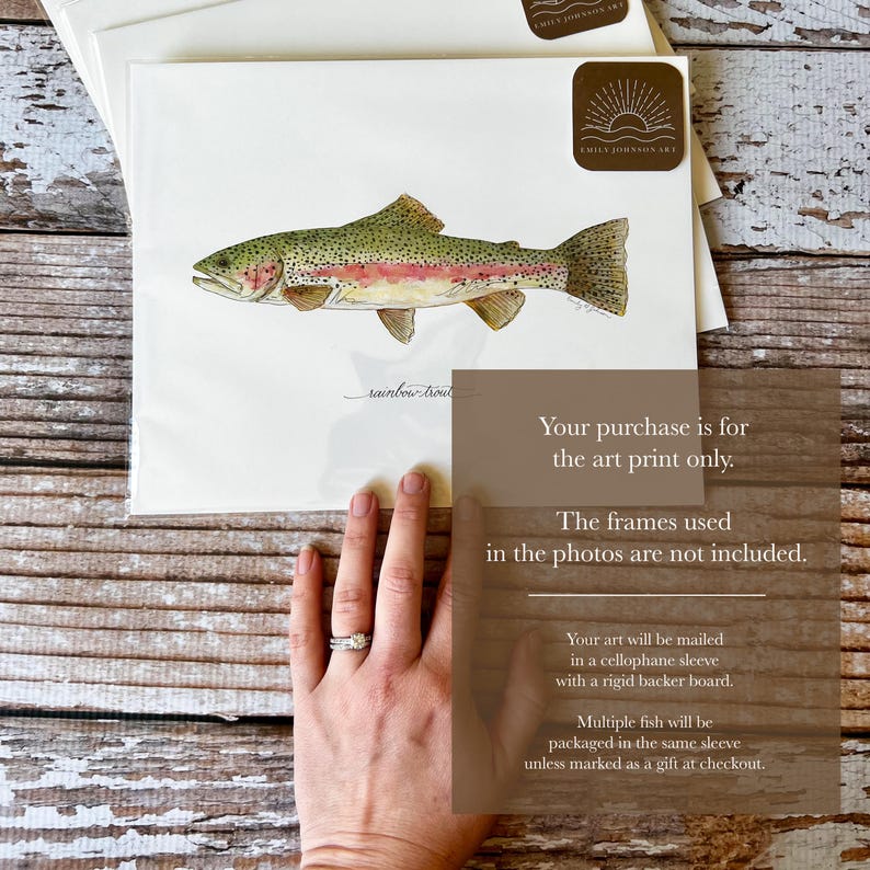 May include: Watercolor art print of a rainbow trout fish. The fish is depicted in shades of green, pink, and gold, with fine details. The print is on white paper, with the artist's signature and logo visible. The art print is packaged in a cellophane sleeve.