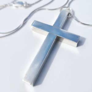 May include: A silver cross pendant necklace with a simple, modern design. The cross is made of thick, rectangular bars and hangs from a delicate silver chain.