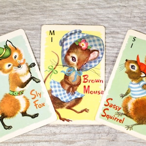 May include: Three illustrated playing cards featuring animal characters. The first card shows a sly fox wearing a green hat and a brown belt. The second card shows a brown mouse wearing a blue and white gingham dress and a blue and white gingham hat. The third card shows a sassy squirrel wearing a red and white striped shirt and a red hat. The cards are labeled "Sly Fox", "Brown Mouse", and "Sassy Squirrel".