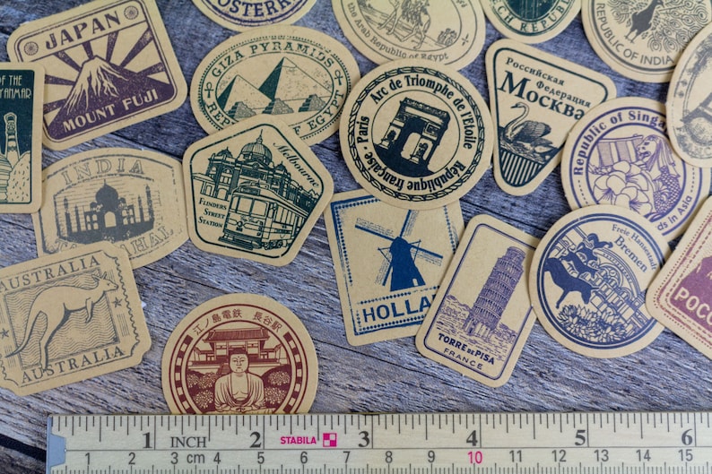 May include: A collection of vintage-style travel stickers featuring landmarks from around the world. Designs include Mount Fuji, the Eiffel Tower, and the Taj Mahal. A ruler shows measurements in inches.
