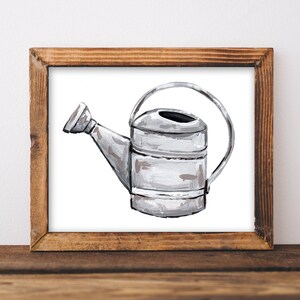 May include: A silver watering can with a handle, painted in a white and gray watercolor style. The watering can is framed in a rustic wooden frame.