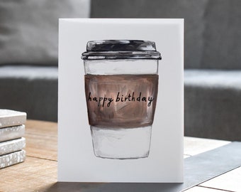 May include: A white card with a hand-drawn illustration of a coffee cup with a brown sleeve that says "happy birthday".