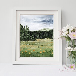 May include: A framed painting of a landscape with a forest in the background and a field of yellow flowers in the foreground. The sky is cloudy and gray.