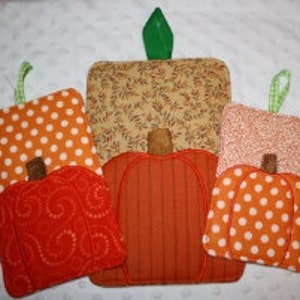 Può includere: Una collezione di cinque presine fatte a mano a forma di zucca. Ogni presina presenta un motivo e un colore diversi, tra cui pois arancioni, stampe floreali e arancione tinta unita. Hanno un anello verde per appenderle e un gambo marrone.