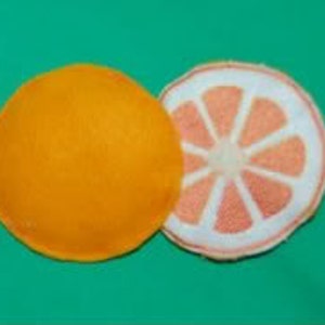 May include: Two felt orange slices, one whole and one cut in half. The cut orange slice has a pink felt centre with white felt lines radiating out from the centre.