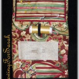 May include: A red and gold paisley fabric sewing kit with a zipper closure. The kit includes scissors, needles, thread, pins, and a pincushion.
