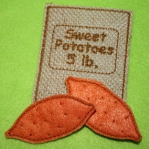 May include: A brown burlap bag with the text "Sweet Potatoes 5 lb." and two orange felt sweet potatoes.