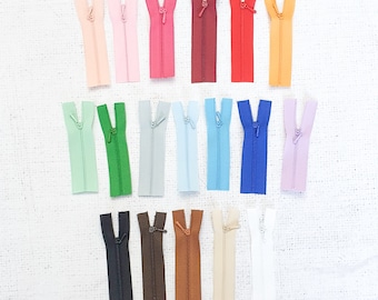 May include: Assortment of 18 zipper pulls in various colors, including pink, red, blue, green, and brown. The zippers are all the same size and are arranged in rows.
