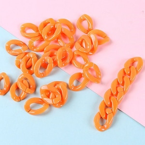 Könnte beinhalten: Eine Sammlung von orangefarbenen Kunststoffkettengliedern, einige sind oval geformt und andere rechteckig. Es gibt eine lange Kette aus rechteckigen Gliedern.
