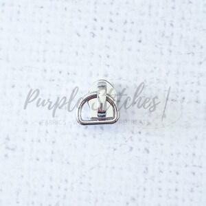 May include: Silver metal D-ring with a hook closure. The D-ring is about 1 inch in diameter.