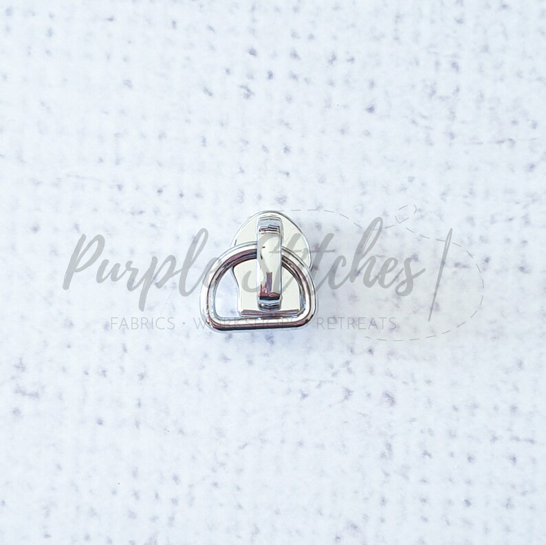 May include: Silver metal D-ring with a hook closure. The D-ring is about 1 inch in diameter.