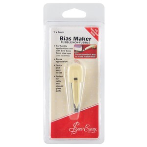 May include: A white plastic bias maker tool for creating fusible bias tape. The tool is packaged in a clear plastic blister pack with instructions on the back. The packaging also includes the text "Bias Maker" and "Sew Easy".