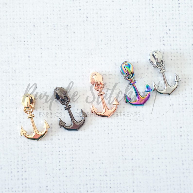 May include: Five zipper pulls in different finishes: gold, black, rose gold, iridescent, and silver. Each pull is shaped like an anchor.