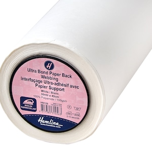 May include: A roll of white Ultra Bond Paper Back Webbing, a fabric interfacing for sewing projects. The label reads "White / Blanc, 30mtr x 45cm". The product is iron-on and made of 100% Polyamide.