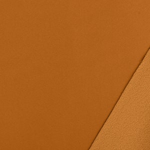 May include: Close-up of two fabric swatches. The top swatch is a solid brown colour, while the bottom swatch is a fuzzy brown fleece.