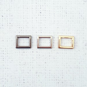 Può includere: Tre cornici rettangolari in metallo in diverse finiture: argento, nichel e oro. Le cornici sono piccole e hanno un design semplice.
